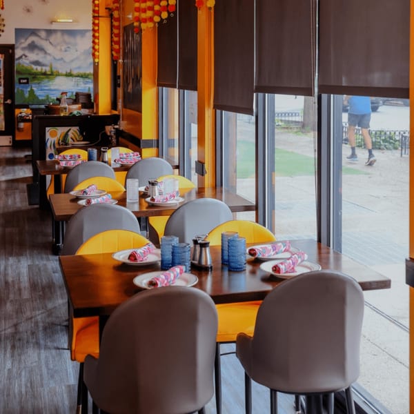Nanglo Restaurant and Bar's dining area with set tables, yellow chairs, and a mountain mural.