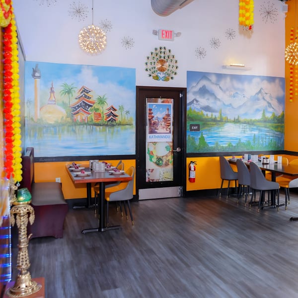 Nanglo Restaurant and Bar's dining area with murals of Nepalese landscapes, tables, and chairs.