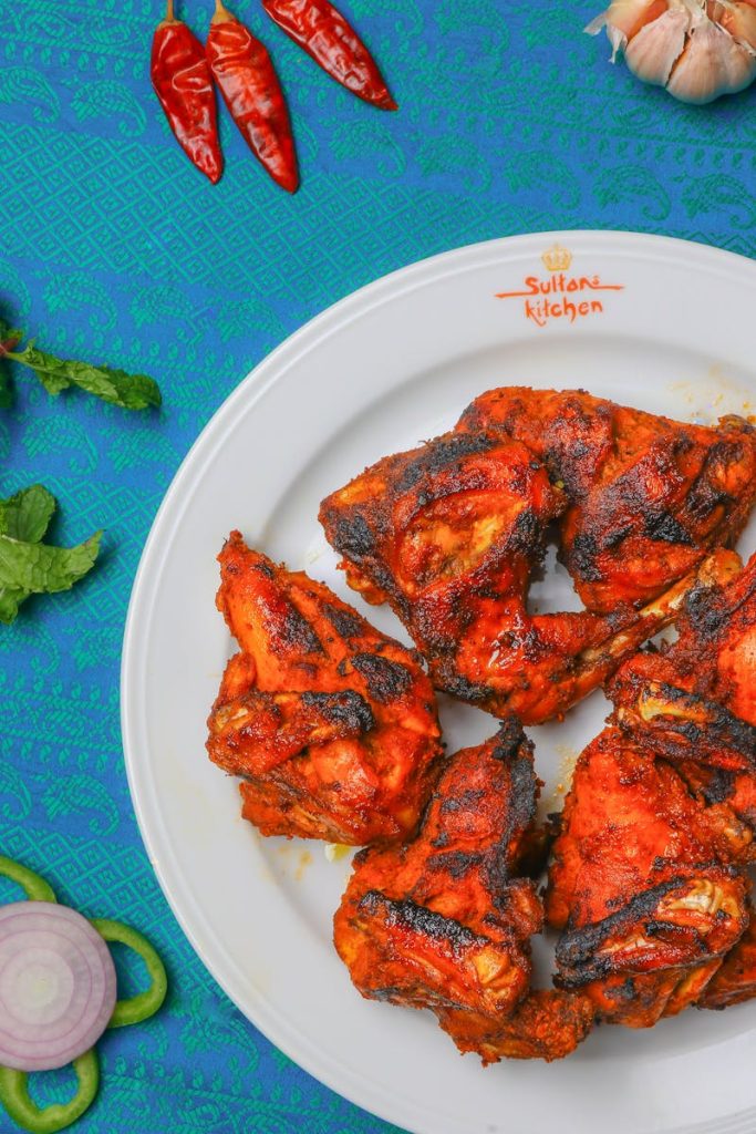 Aromatic grilled chicken pieces served on a white plate with colorful spices.