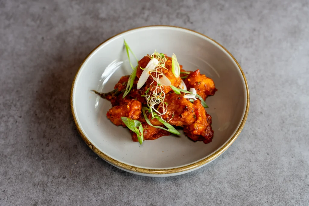 Aromatic grilled chicken pieces served on a white plate with colorful spices.