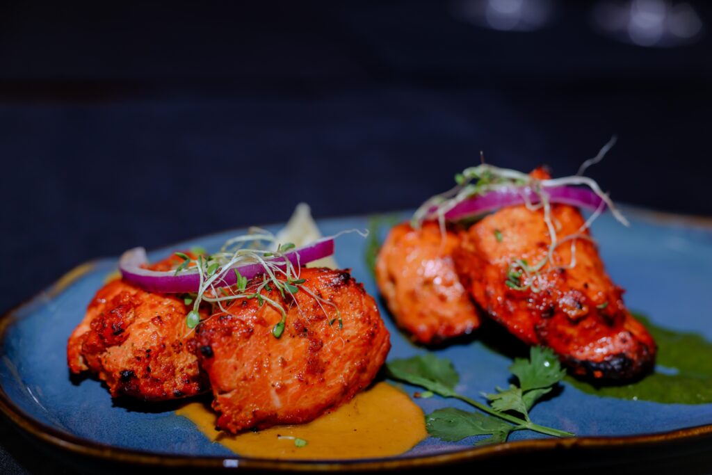 Aromatic grilled chicken pieces served on a white plate with colorful spices.